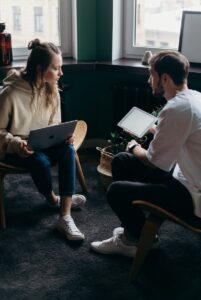 Photo of Couple Talking While Holding Laptop and Ipad